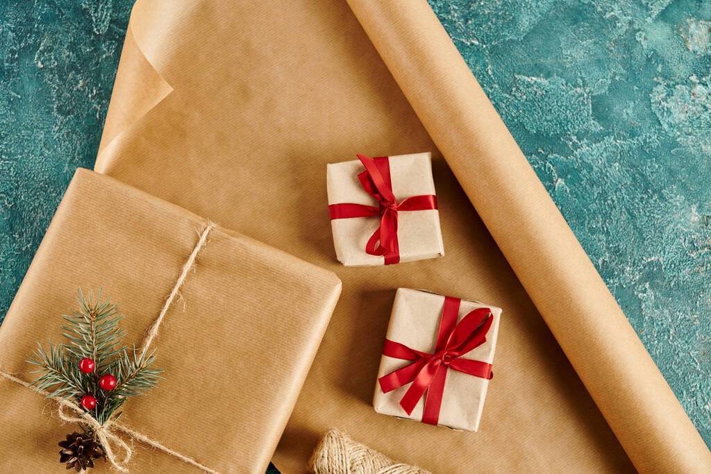 caixas de presente com fitas e ramo de pinho com bagas de azevinho em papel artesanal e superfície texturizada azul - Foto, Imagem