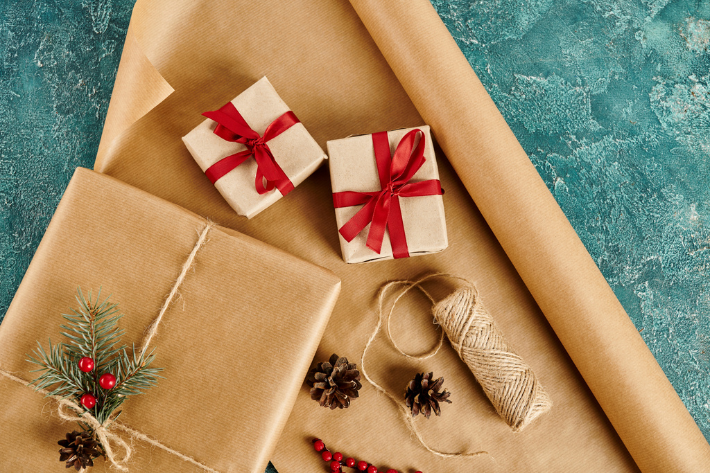versierde geschenkdozen in de buurt van dennenappels en bindgaren met ambachtelijk papier op blauwe achtergrond, diy vakantie ambachten - Foto, afbeelding
