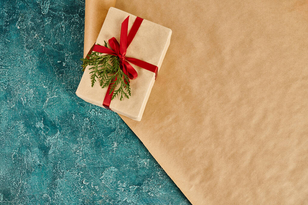 coffret cadeau avec ruban rouge et branche de genévrier vert sur papier d'emballage et textures bleues en toile de fond - Photo, image