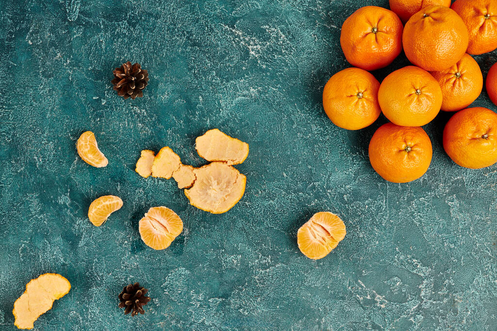 top view of juicy tangerines and pine cones on blue rustic surface, colorful Christmas background - Photo, Image