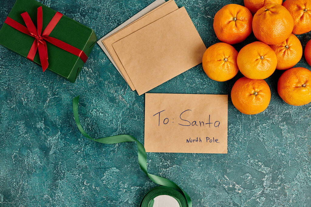 letter to santa at north pole near mandarins and gift box with ribbon on blue textured backdrop - Photo, Image