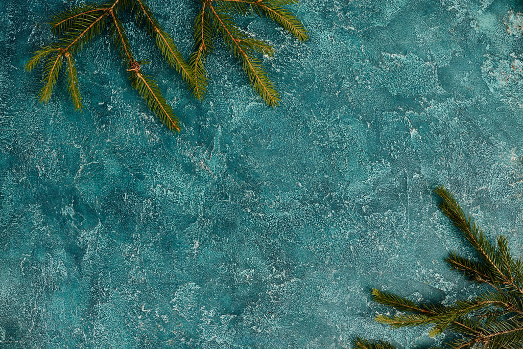 bovenaanzicht van groene dennentakken op blauwe textuur achtergrond met lege ruimte, Kerst achtergrond - Foto, afbeelding