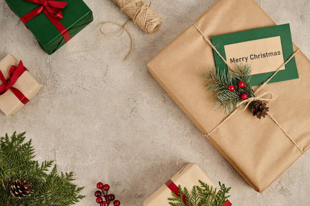 Feliz Natal cartão de saudação perto de caixas de presente decoradas em fundo texturizado cinza, tema de festa - Foto, Imagem