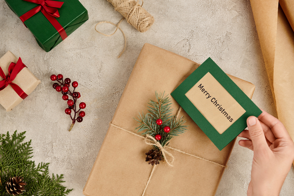 κουτί δώρου με ευχετήρια κάρτα Καλά Χριστούγεννα κοντά δώρα και εποχιακή διακόσμηση σε υφή επιφάνεια - Φωτογραφία, εικόνα