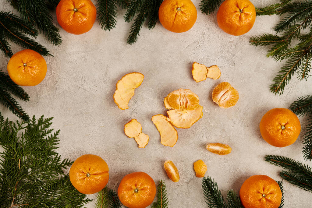 mandarines moulues dans le cadre de branches de genévrier et de pin sur fond gris texturé, Noël - Photo, image
