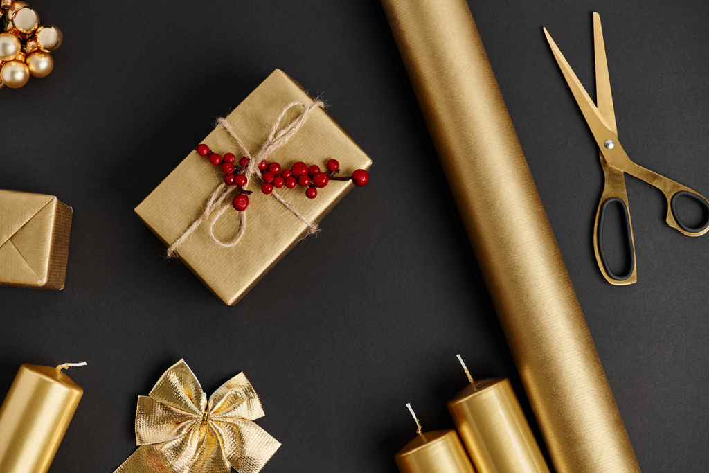 goldene und glänzende Weihnachtsobjekte auf Schwarz, Scheren in der Nähe von Papierrollen und Kerzen, Bastelarbeiten - Foto, Bild