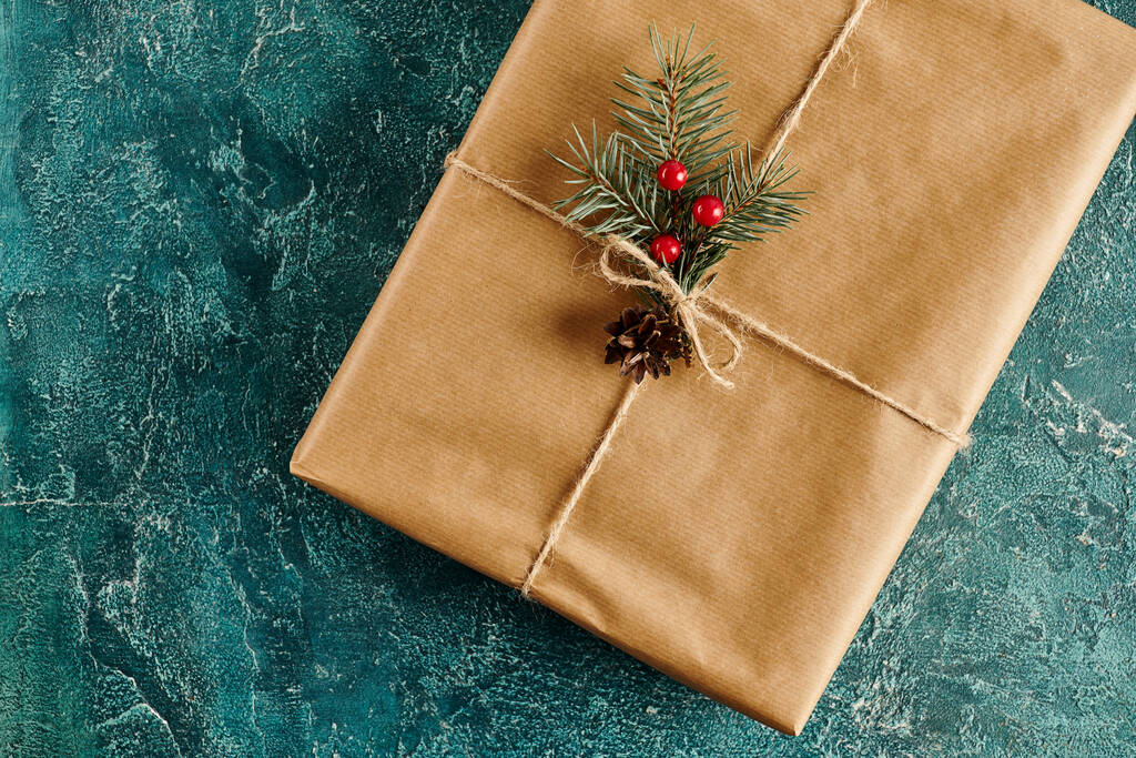 Cadeau de Noël décoré de branches de pin et de baies de houx sur fond texturé bleu - Photo, image