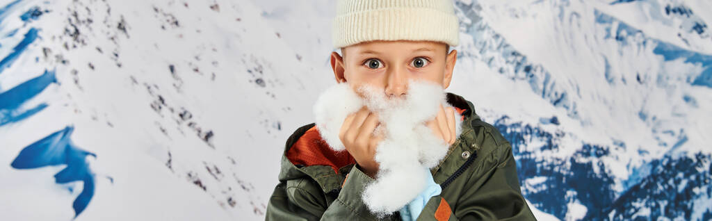 roztomilý chlapec v čepici se sněhem v rukou v blízkosti obličeje, při pohledu na kameru, módní koncept, banner - Fotografie, Obrázek