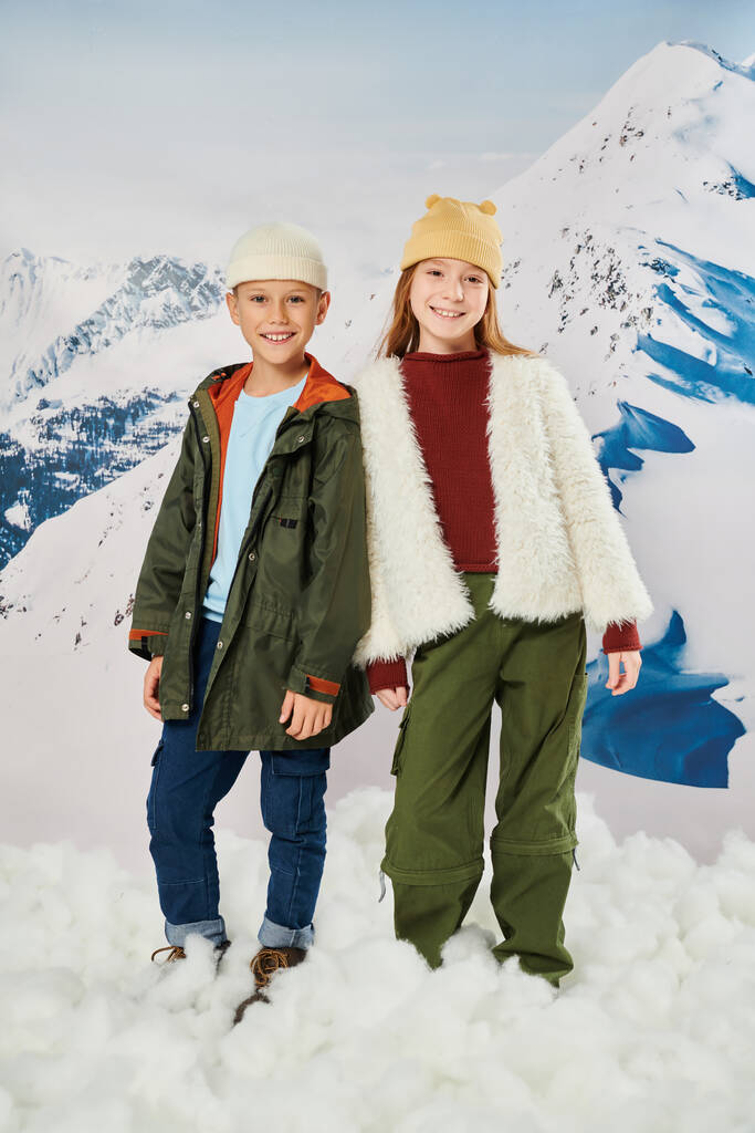 tiro vertical de crianças pequenas alegres no inverno traje elegante sorrindo alegremente para a câmera, moda - Foto, Imagem