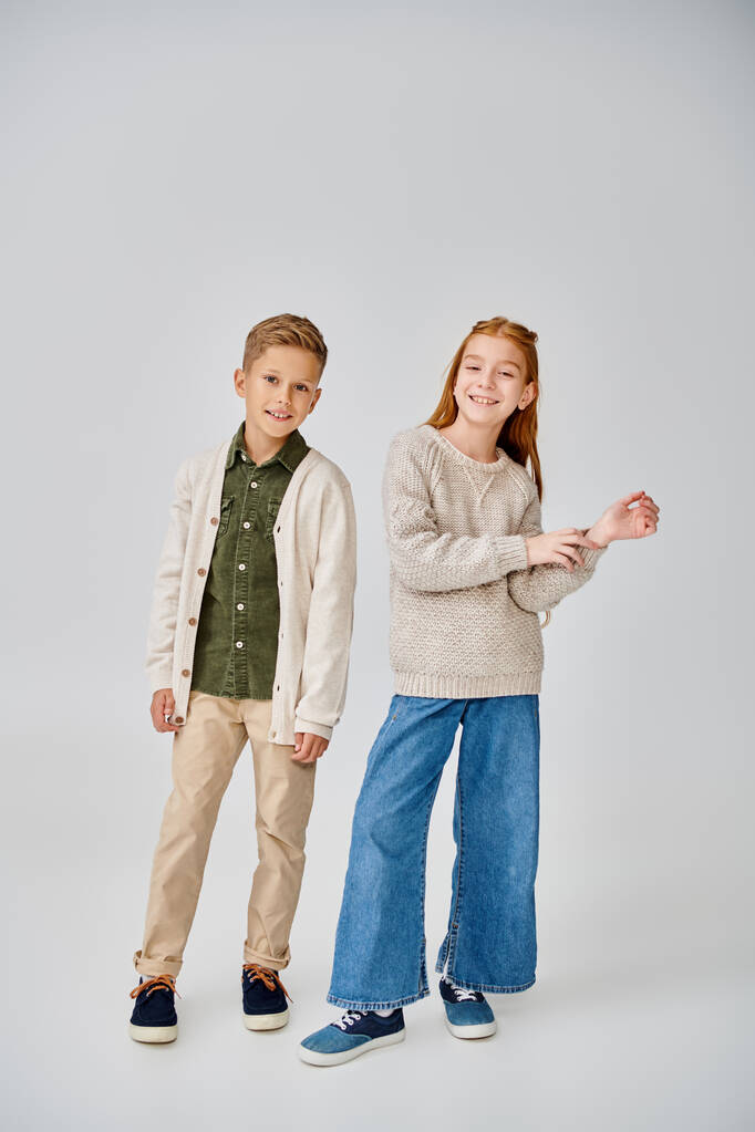 cheerful preadolescent children in stylish casual clothes posing on gray backdrop, smiling at camera - Photo, Image