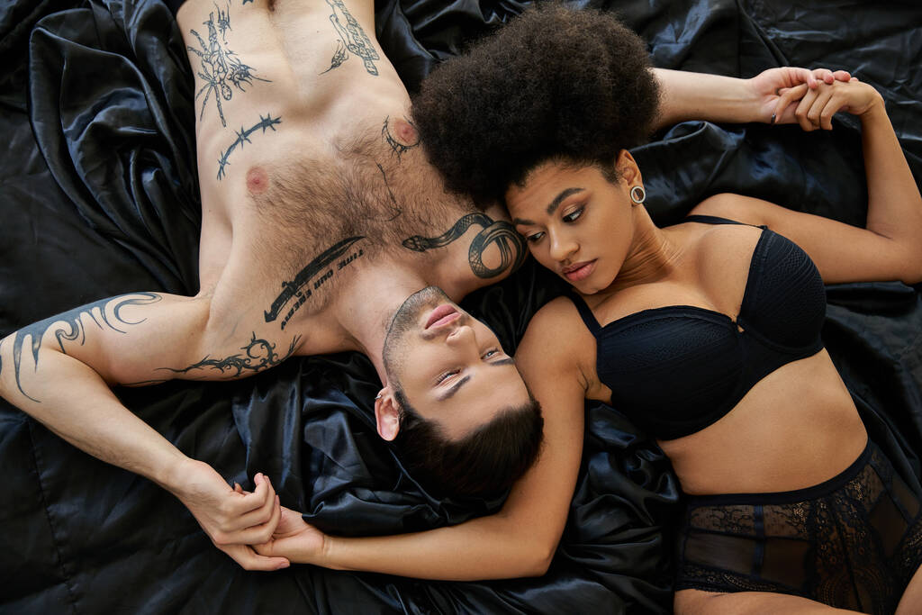 hermosa mujer afroamericana en ropa interior acostada en la cama junto a su novio, sexy pareja - Foto, imagen