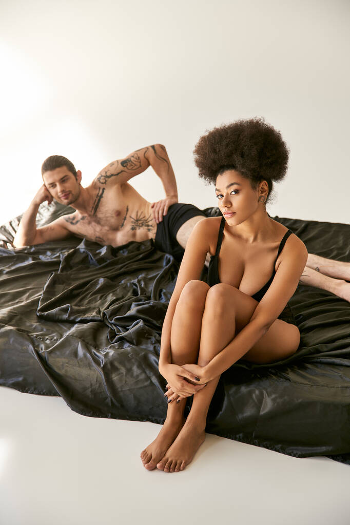зосередитися на афроамериканській жінці в сексуальній білизні, сидячи поруч зі своїм розмитим хлопцем, сексуальна пара - Фото, зображення