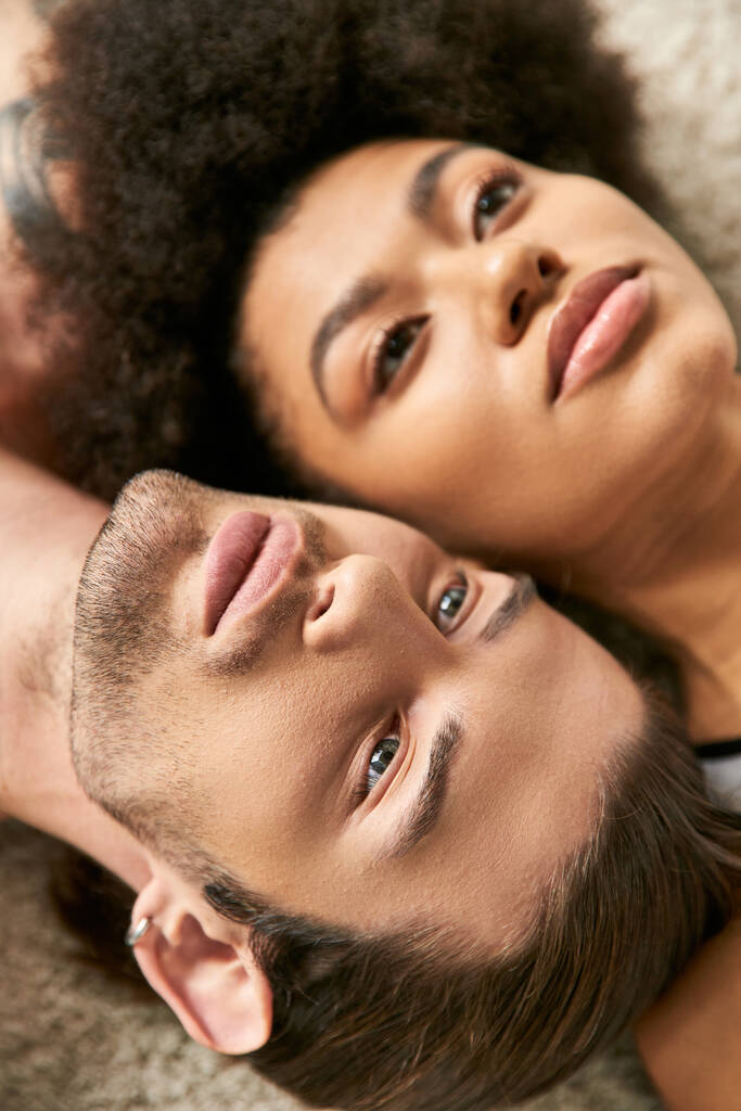 primer plano de buen aspecto sexy pareja multicultural acostado sensualmente juntos y mirando hacia otro lado - Foto, Imagen