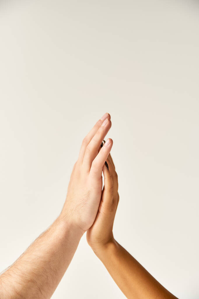 bijgesneden weergave van interraciale sexy paar aanraken handen en vingers van elkaar op ecru achtergrond - Foto, afbeelding