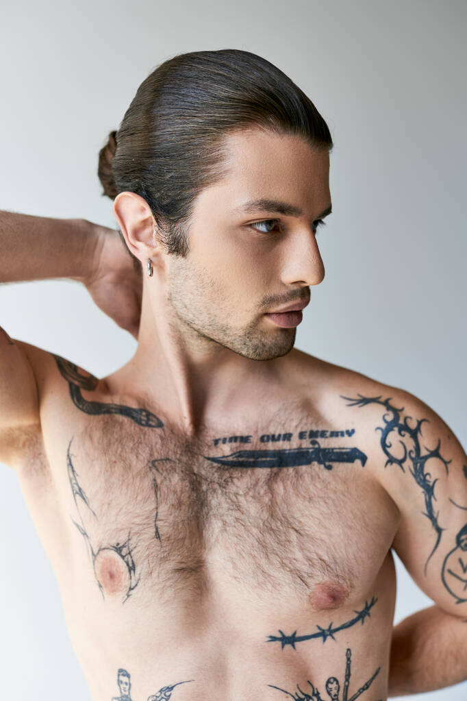 seksikäs hyvännäköinen mies poninhäntä ja tatuoinnit mukava alusvaatteet poseeraa ecru tausta - Valokuva, kuva