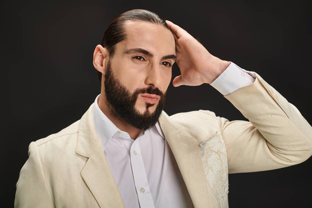 hombre árabe elegante y barbudo en camisa blanca y chaqueta mirando hacia otro lado sobre fondo negro - Foto, Imagen