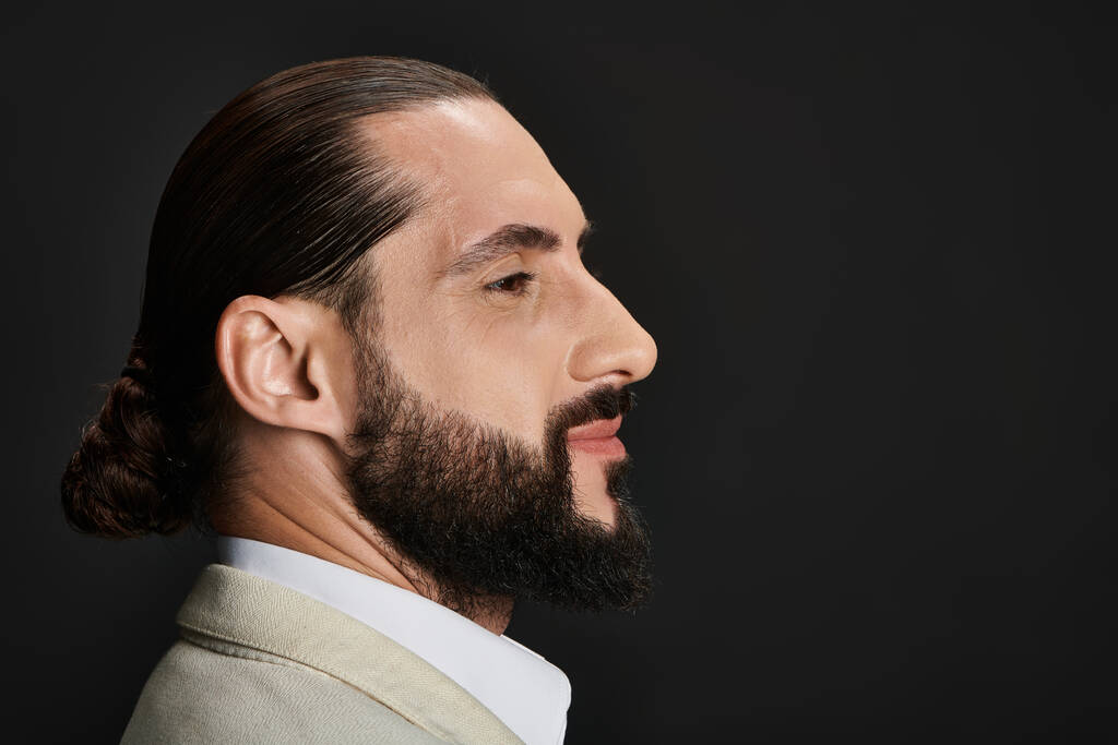 vista lateral, retrato de hombre árabe barbudo y confiado en camisa blanca posando sobre fondo negro - Foto, imagen