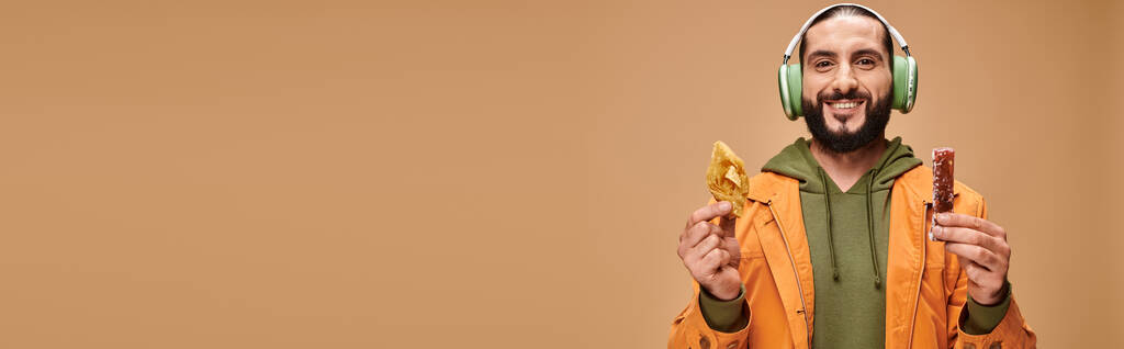 счастливый человек в наушниках с двумя ближневосточными десертами, медовая пахлава и церковное знамя - Фото, изображение