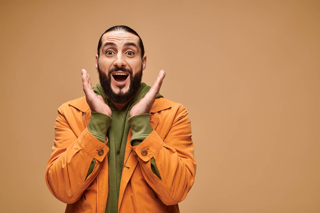 surpris homme du Moyen-Orient avec barbe et bouche ouverte gestuelle sur fond beige, wow - Photo, image