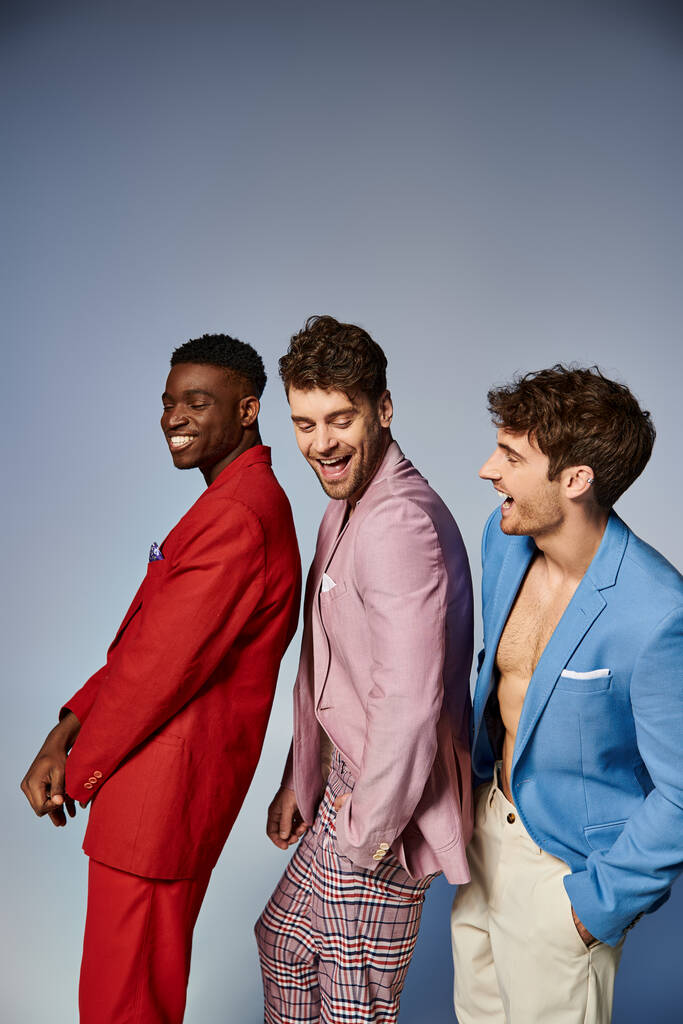 веселый красивый разнообразных мужчин в стильных ярких костюмах позируя в одном файле на сером фоне - Фото, изображение