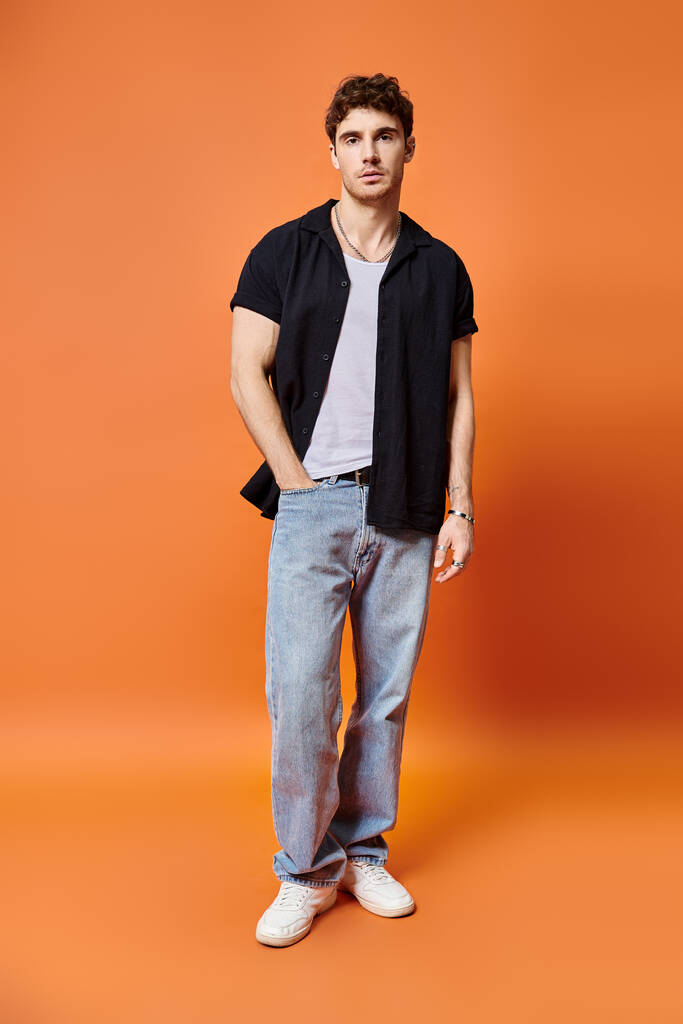 good looking young man in street outfit on orange backdrop looking at camera, fashion concept - Photo, Image