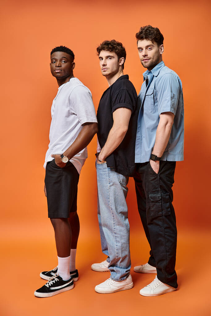 attraktive, elegante Freunde in urbaner Kleidung posieren vor orangefarbenem Hintergrund, Modekonzept - Foto, Bild