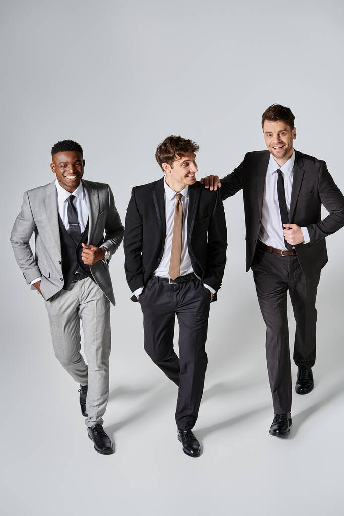 fashionable happy diverse friends in business elegant attires smiling joyfully on gray background - Photo, Image