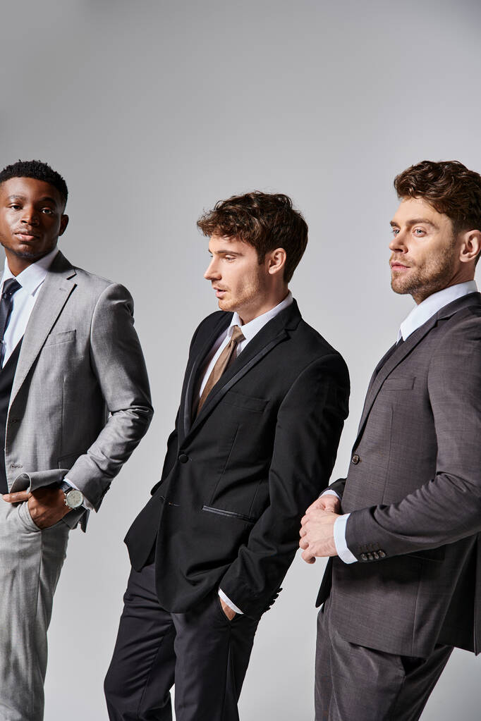 vonzó elegáns multikulturális férfi modellek üzleti elegáns elegáns öltöny pózol szürke háttér - Fotó, kép