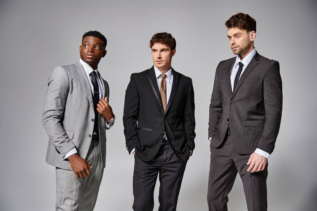 handsome stylish diverse male models in business elegant smart suits posing on gray backdrop - Photo, Image