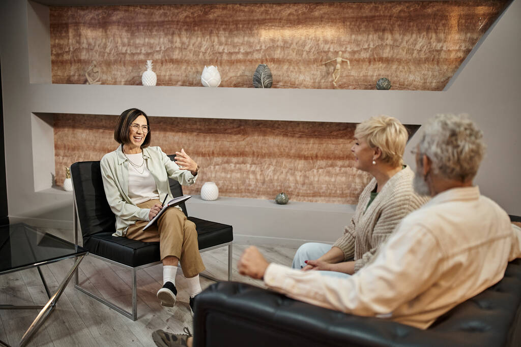 positieve psycholoog gebaren tijdens het praten met echtpaar van middelbare leeftijd tijdens therapie sessie - Foto, afbeelding
