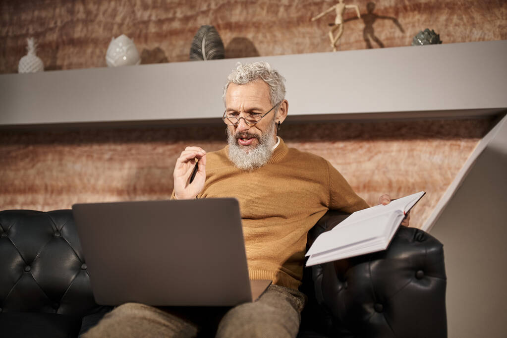 psycholoog van middelbare leeftijd met baard in gesprek met klant tijdens virtueel consult op laptop - Foto, afbeelding