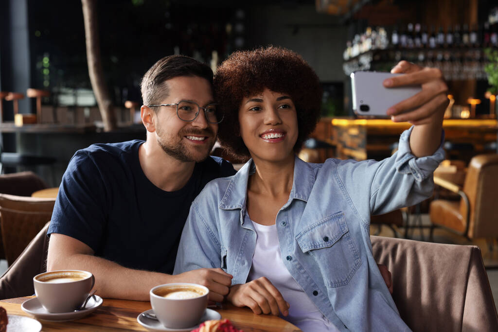 Διεθνή ραντεβού. Ευτυχισμένο ζευγάρι βγάζει selfie στο cafe - Φωτογραφία, εικόνα