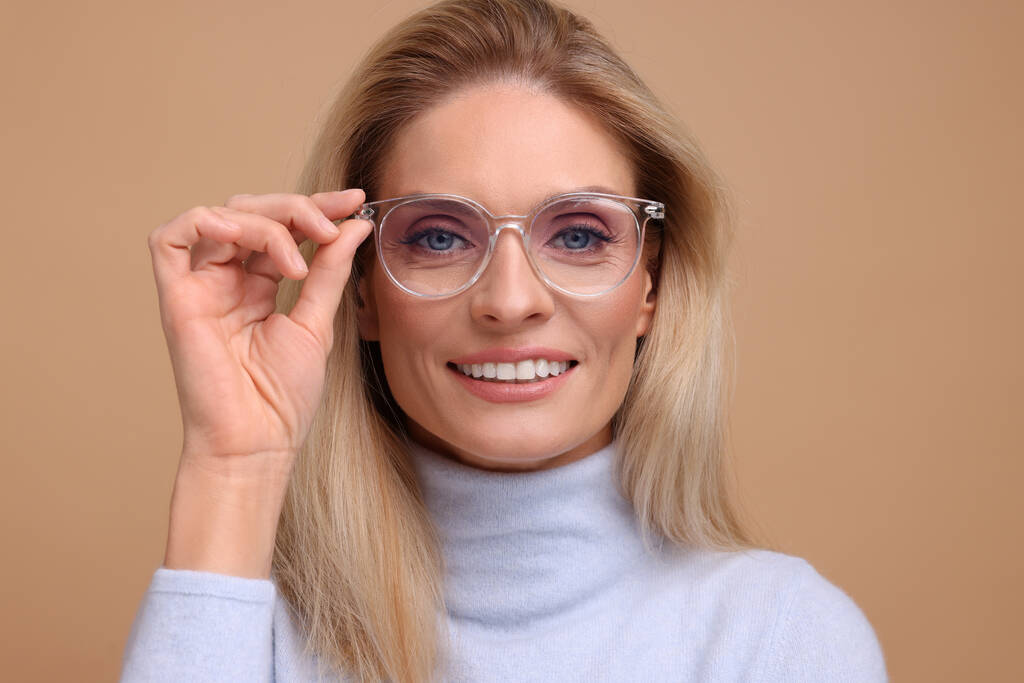 Portré mosolygós középkorú nő szemüvegben bézs háttér - Fotó, kép