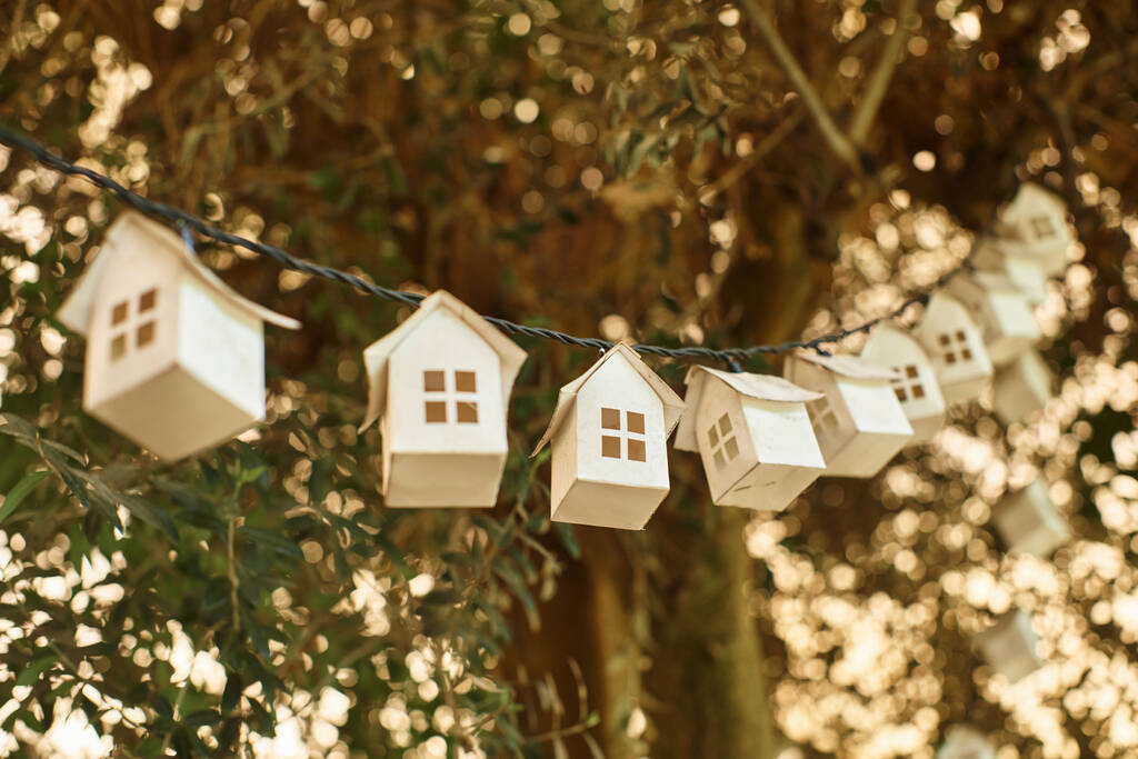 ekologiczna girlanda z drewnianych domów na zielonym drzewie ze świeżymi liśćmi wewnątrz szklarni - Zdjęcie, obraz