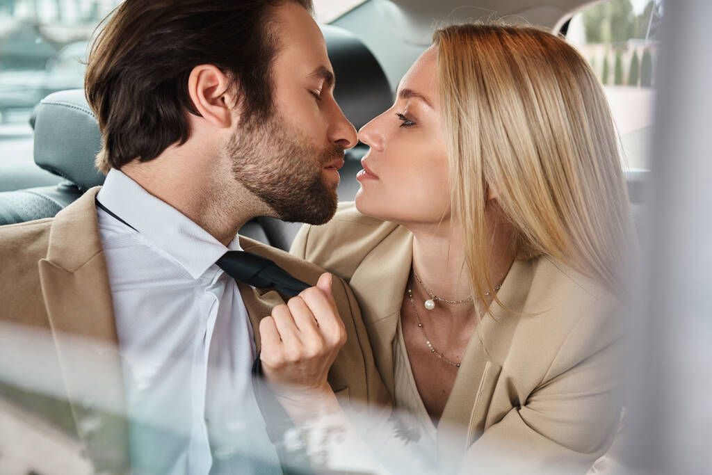 aantrekkelijke en sensuele blonde zakenvrouw verleiden knappe bebaarde zakenman in auto, romantiek - Foto, afbeelding
