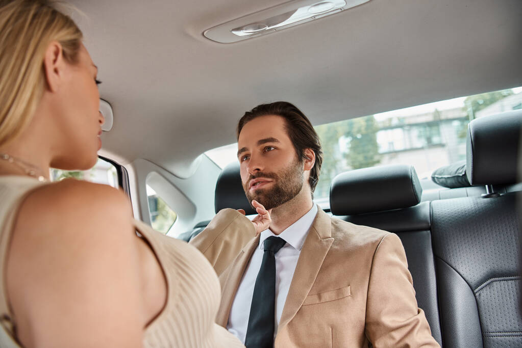 情熱的なブロンドのビジネスマンは,車で旅行中に優雅なビジネスパートナーを魅了 - 写真・画像