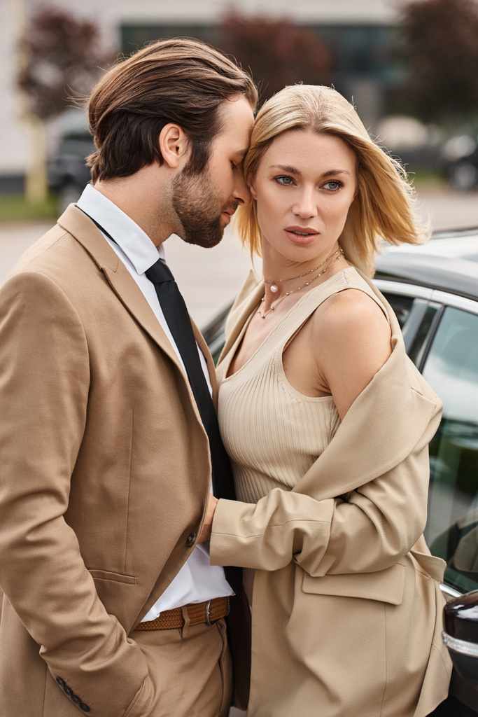 γοητευτική ξανθιά επιχειρηματίας αγκαλιάζει κομψό άνδρα κοντά στο αυτοκίνητο στο δρόμο, έλξη και αγάπη - Φωτογραφία, εικόνα