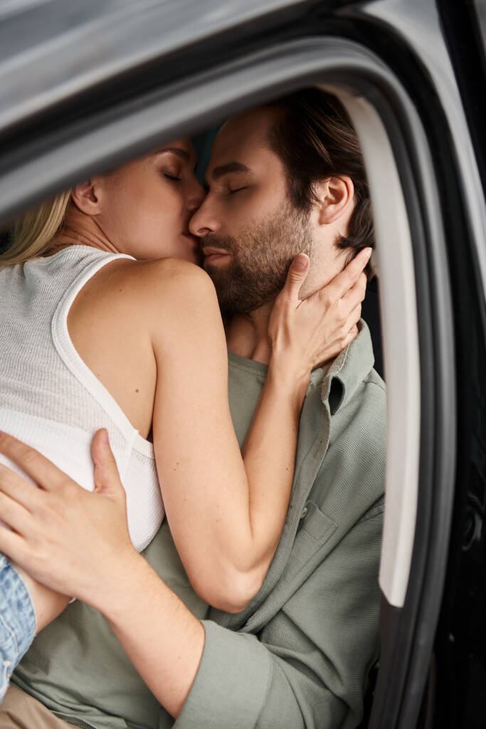 пристрасна стильна пара обіймає і цілує в сучасній машині на вулиці міста, кохання і близькість - Фото, зображення