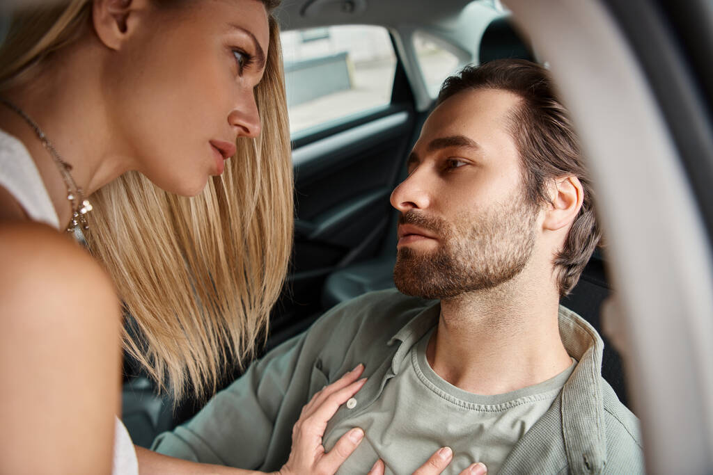 szenvedélyes szőke nő elcsábítja szakállas férfi ül autóban a városi utcán, városi romantika - Fotó, kép