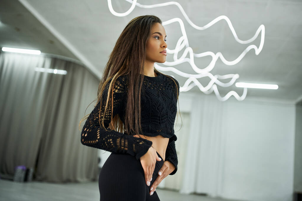 joven afroamericana de pelo largo en traje negro ensayando danza en estudio, arte - Foto, imagen