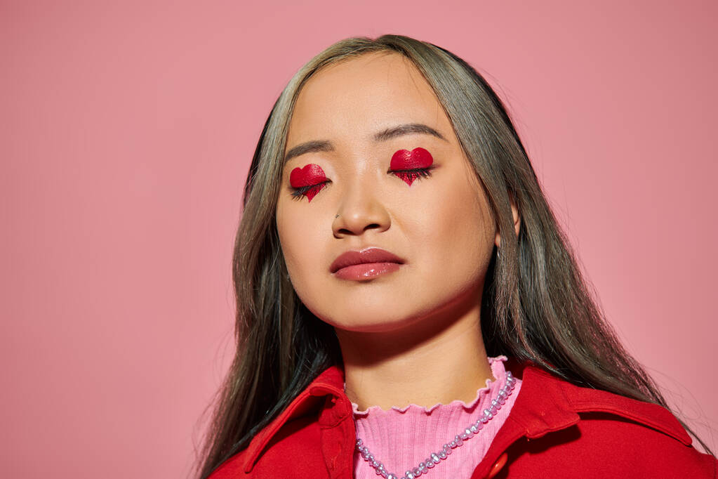 Valentines day concept, young asian woman with heart shaped eye makeup and closed eyes on pink - Photo, Image