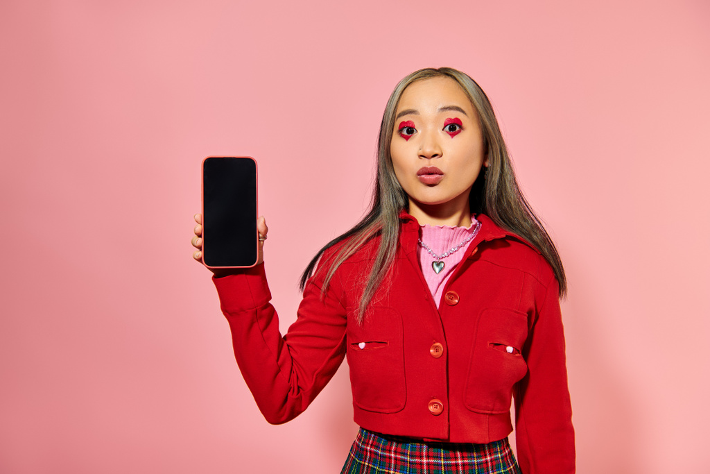 fiatal ázsiai nő piros Valentin nap smink mutatja okostelefon üres képernyő rózsaszín - Fotó, kép