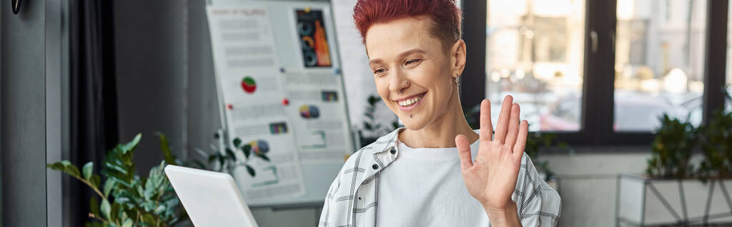 zufriedener Bigender-Manager winkt bei Videoanruf auf digitalem Tablet in modernem Büro, Banner - Foto, Bild