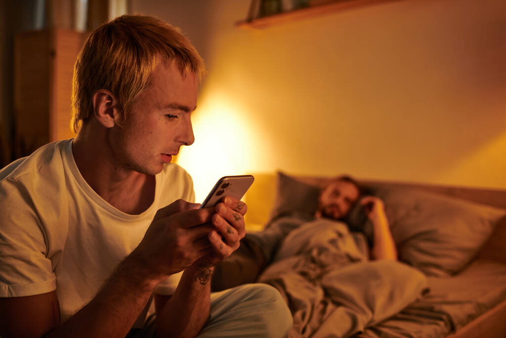 homme gay déloyal messagerie sur téléphone mobile près de petit ami dormir la nuit dans la chambre, tricherie - Photo, image