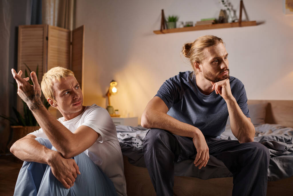 gej człowiek rozmawiając z zdenerwowany i obrażony miłość partner siedzi w nocy w sypialnia kłopoty miłość - Zdjęcie, obraz
