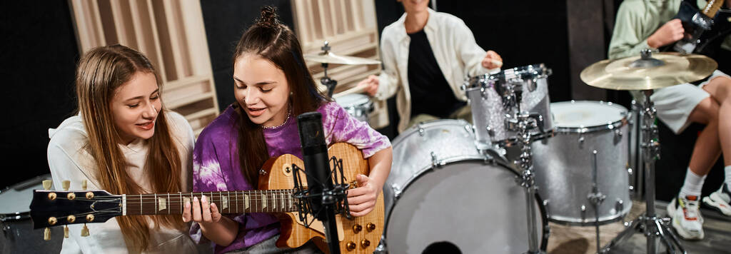 concentrarsi su ragazze adolescenti allegre che suonano la chitarra e cantano vicino ai loro amici offuscati, striscione - Foto, immagini