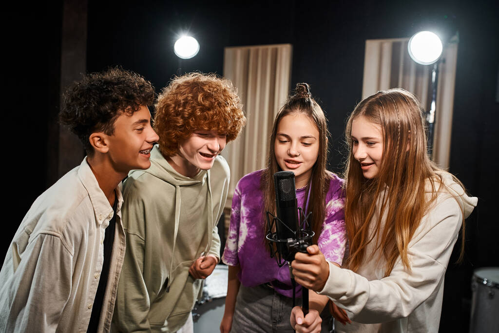 four joyous talented teenagers in casual outfits singing together while in studio, musical group - Photo, Image
