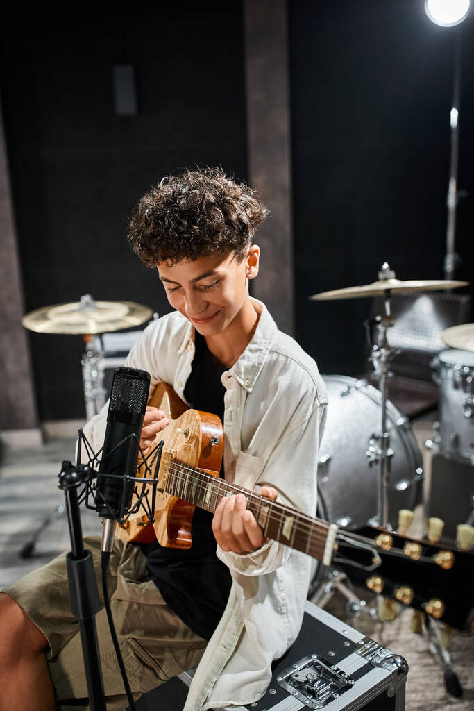 vrolijk schattig getalenteerd tiener jongen in alledaagse kleding spelen gitaar en glimlachen gelukkig - Foto, afbeelding