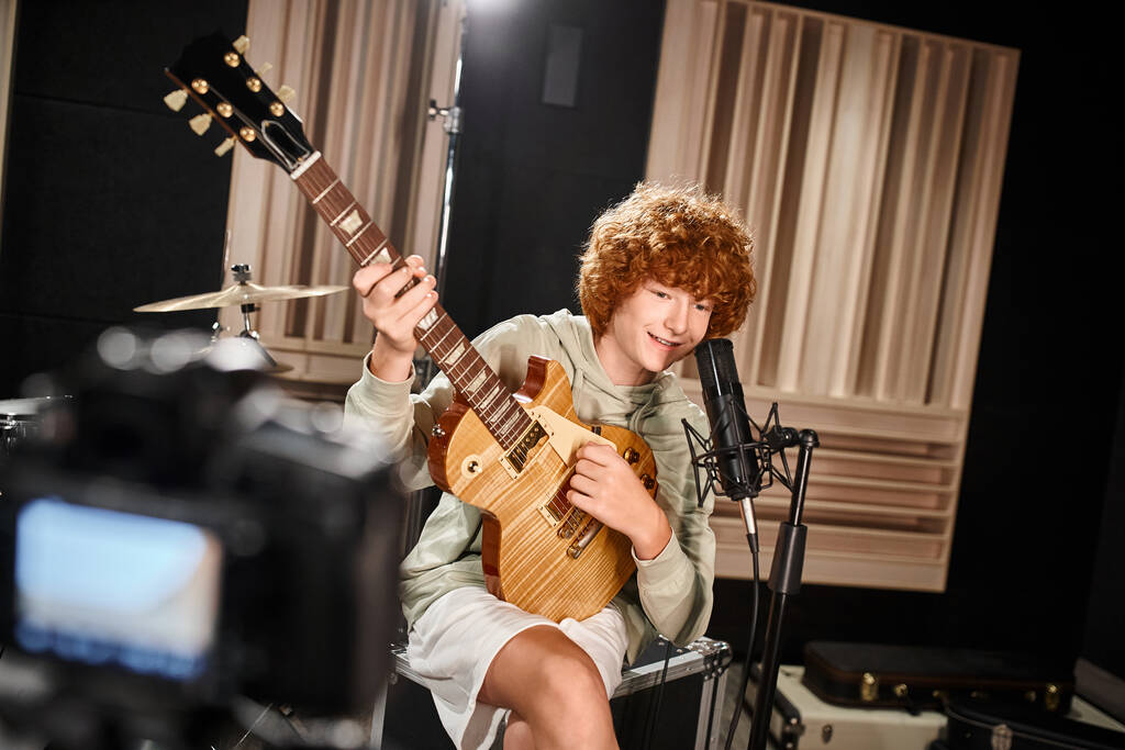 fröhlicher süßer Teenager in Alltagskleidung, der Gitarre spielt und ins Mikrofon singt - Foto, Bild