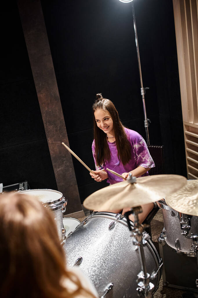 vrolijk mooi tiener meisje in levendige kleren spelen gitaar en glimlachen gelukkig in de studio - Foto, afbeelding